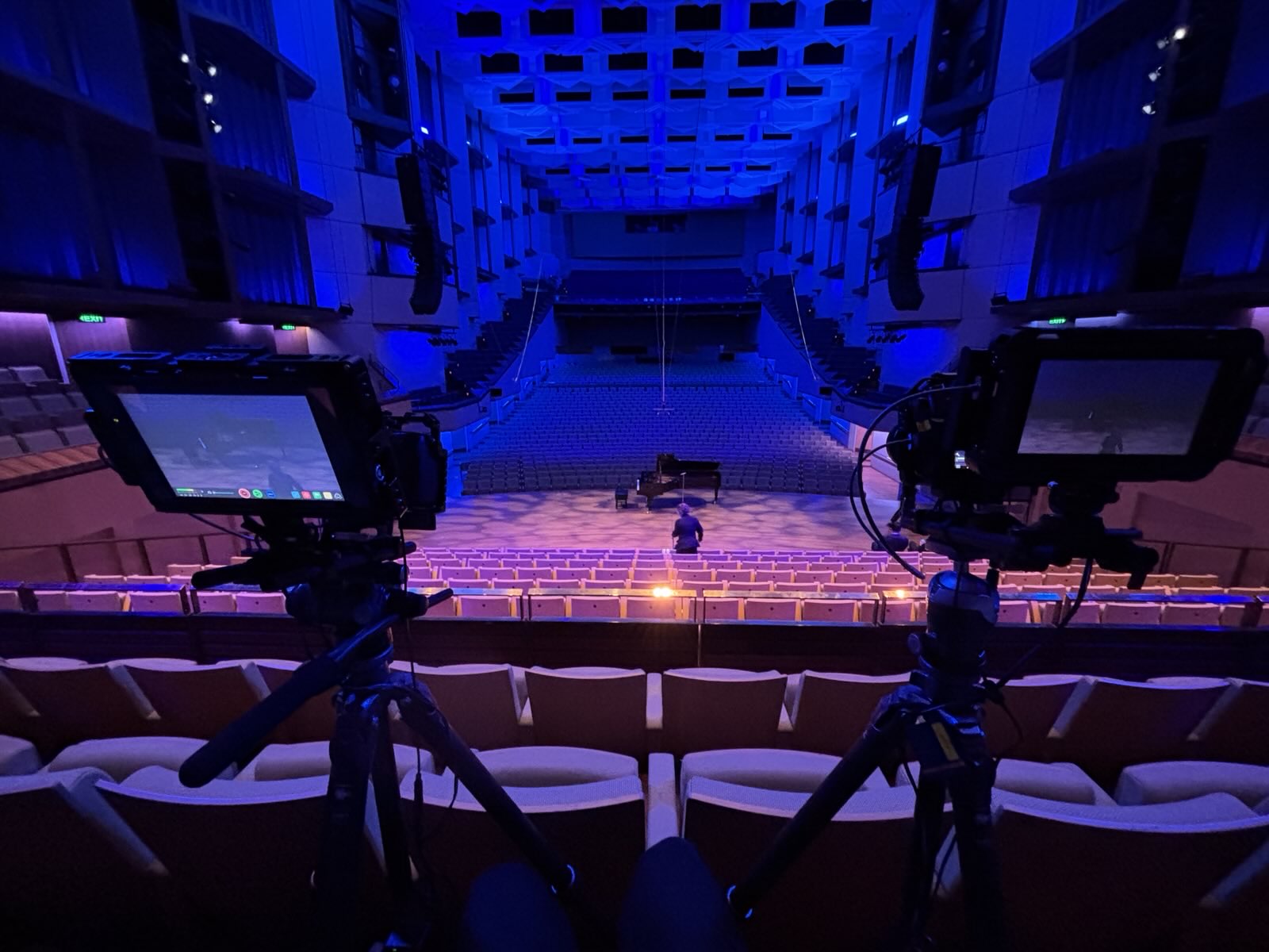 Cameras recording a piano recital in a concert hall.